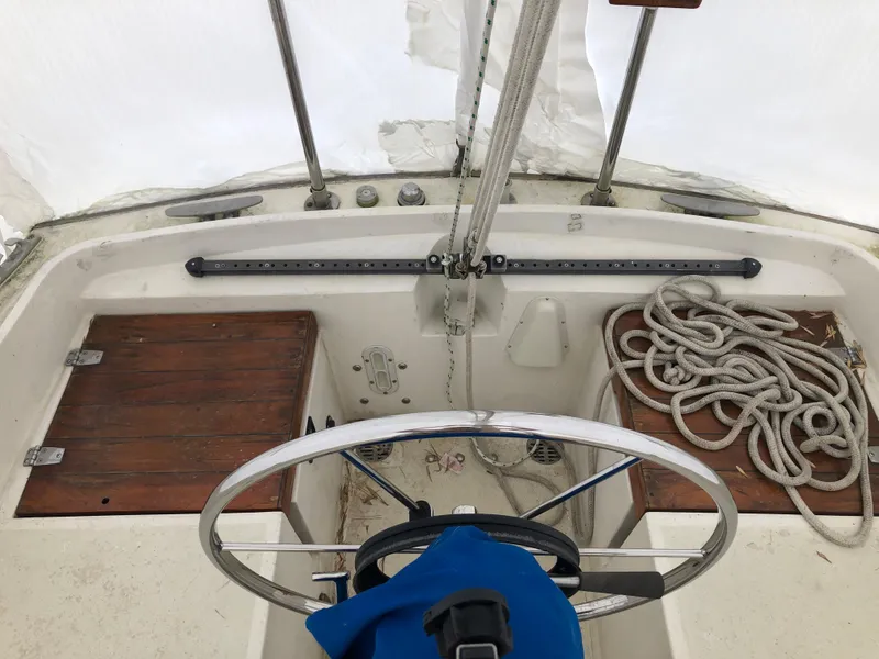 Slide: The Image of 1976 Tartan 30 sailboat cockpit with steering wheel, wooden seats, and coiled rope. - 16