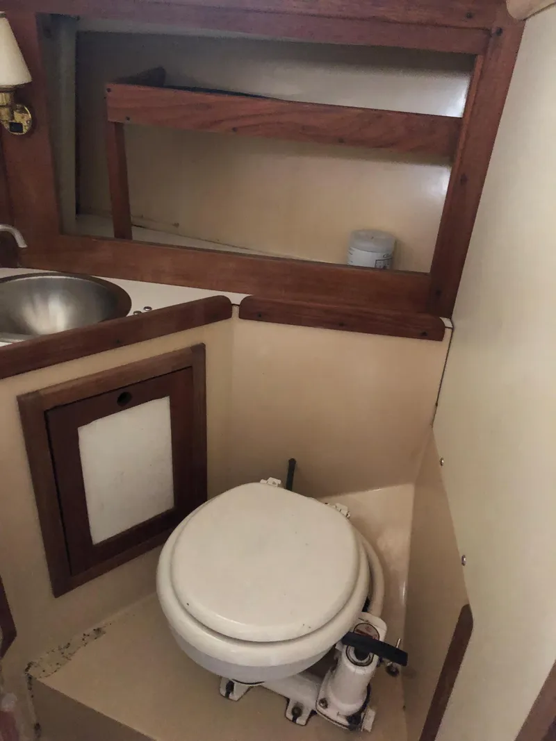 Slide: The Image of 1976 Tartan 30 sailboat bathroom with toilet, sink, and wooden storage shelf. - 22