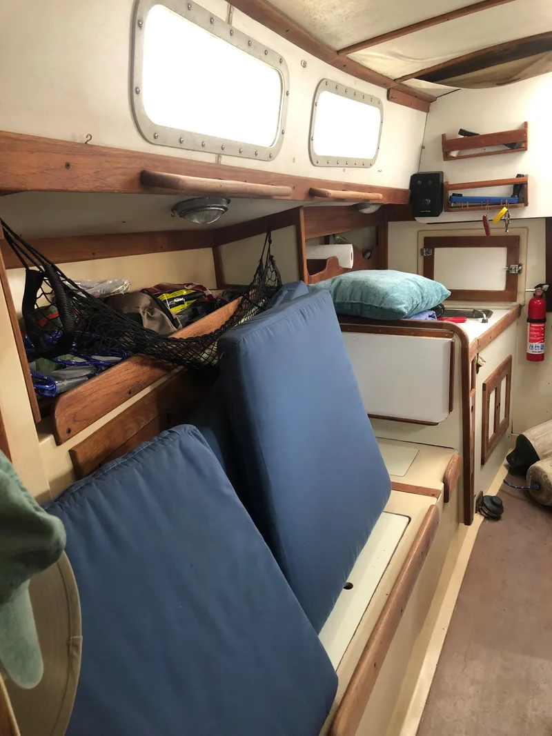 Slide: The Image of 1976 Tartan 30 sailboat interior with blue cushions, storage, and safety equipment. - 24
