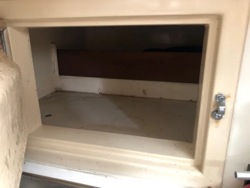 Slide: The Image of Empty storage compartment in a 1976 Tartan 30 sailboat, featuring a beige interior. - 28