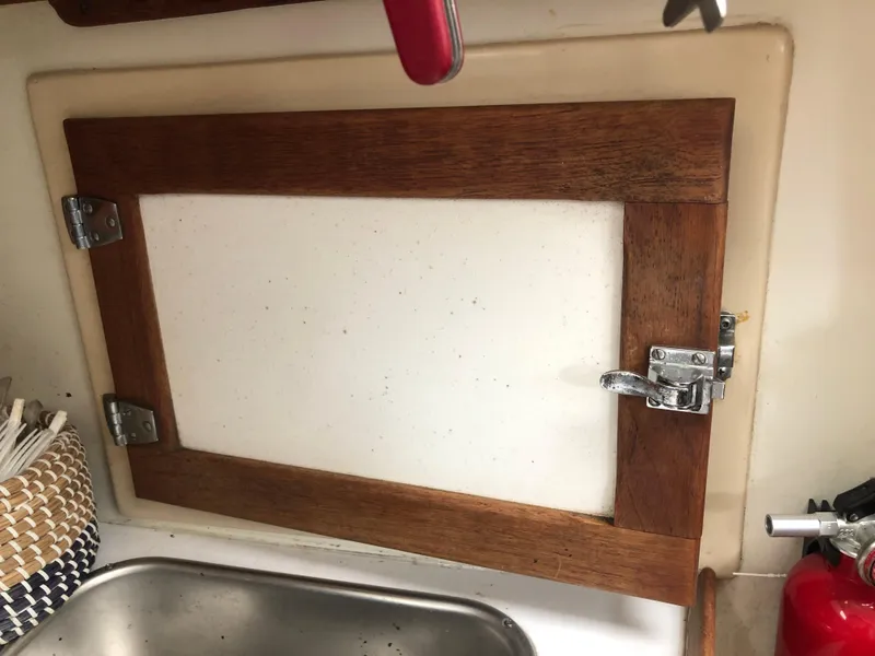 Slide: The Image of Wooden cabinet door with metal latch in a 1976 Tartan 30 boat kitchen. - 29