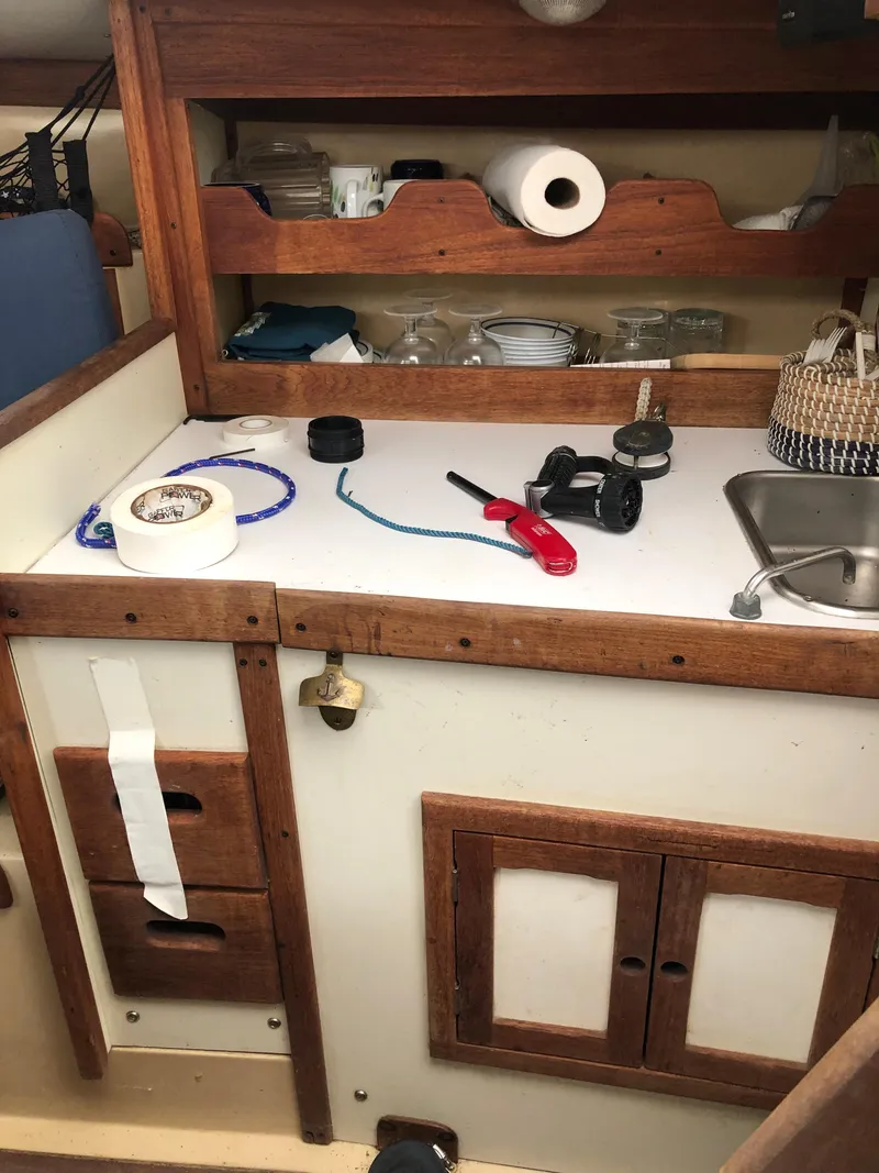 Slide: The Image of 1976 Tartan 30 sailboat galley with wooden cabinets, sink, and various kitchen items. - 31