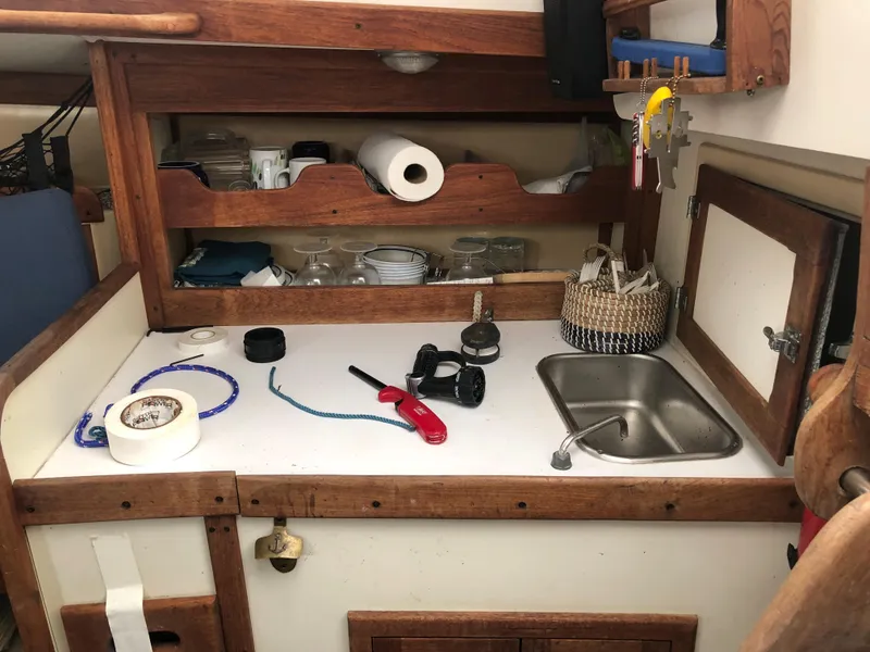 Slide: The Image of 1976 Tartan 30 sailboat galley with sink, shelves, and various kitchen items. - 32