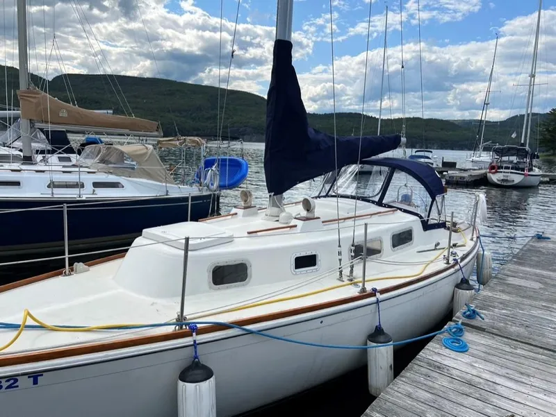 Slide: The Image of 1976 Tartan 30 sailboat docked at a marina, surrounded by other boats, under a partly cloudy sky. - 33