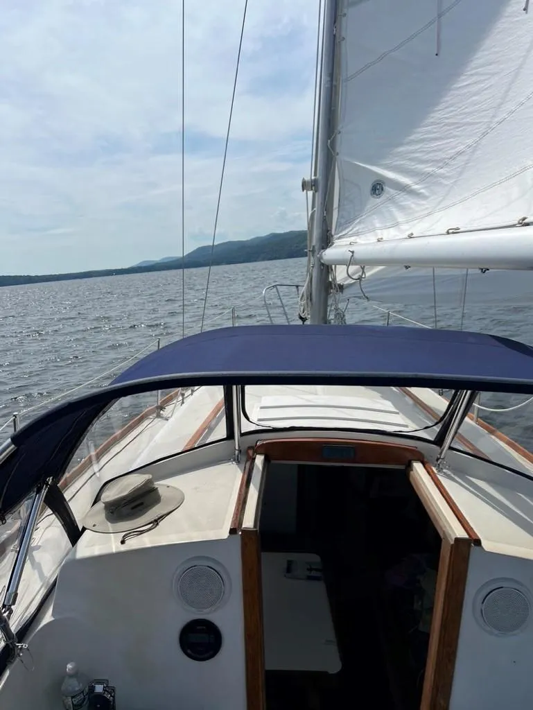 Slide: The Image of 1976 Tartan 30 sailboat on open water, featuring sails and cockpit with a hat on deck. - 37
