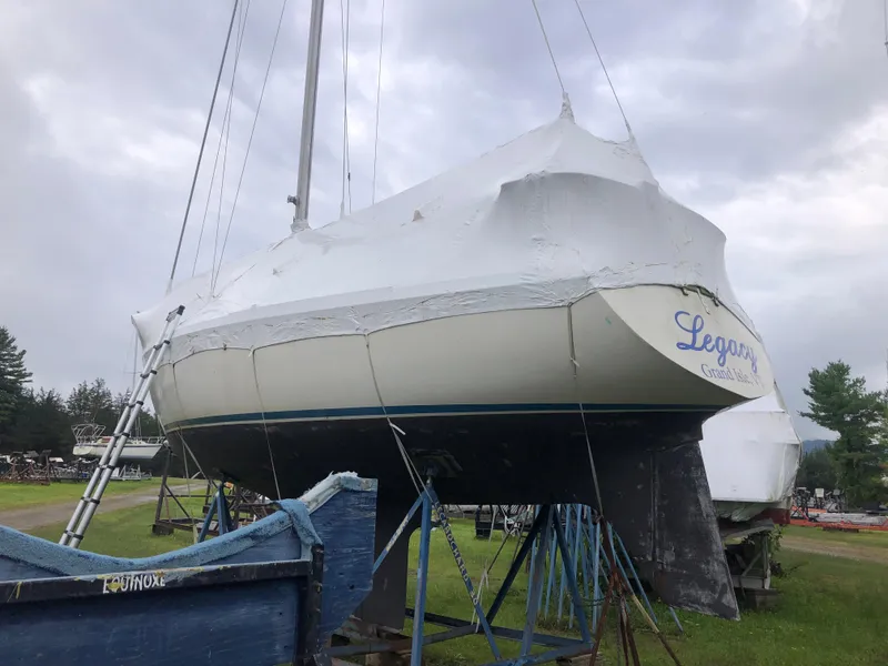 Slide: The Image of 1976 Tartan 30 sailboat covered in protective wrap, elevated on stands, with overcast sky. - 6