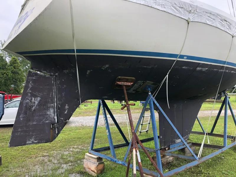 Slide: The Image of 1976 Tartan 30 sailboat on stands, showing hull and rudder, in a grassy outdoor setting. - 8