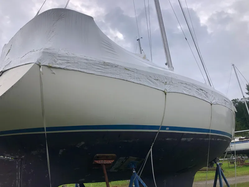 Slide: The Image of 1976 Tartan 30 sailboat covered in protective wrap, displayed on stands outdoors. - 9