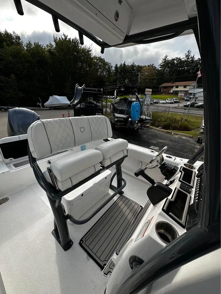 Slide: The Image of 2024 Sea Fox 248 Commander boat interior with seating and console, parked outdoors. - 7