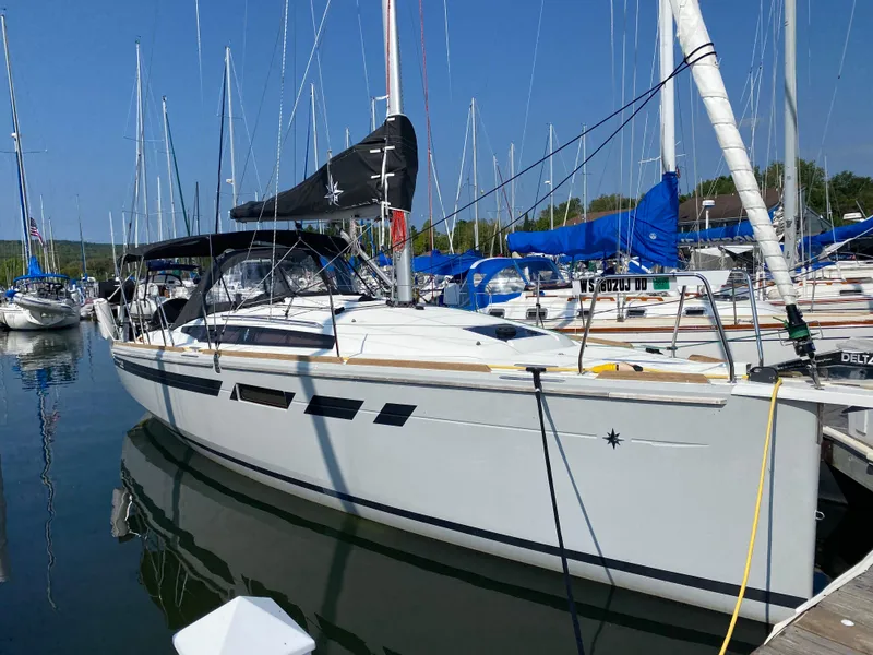 The Image of 2023 Jeanneau Sun Odyssey 349 sailboat docked in a marina, surrounded by other boats. - 0