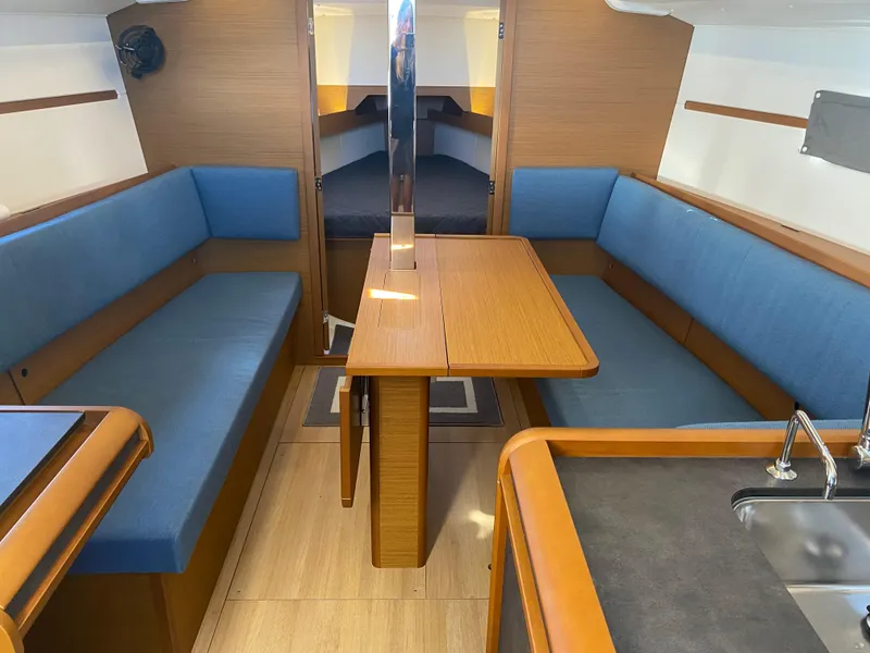 Slide: The Image of Interior of 2023 Jeanneau Sun Odyssey 349 sailboat with blue seating and wooden table. - 11