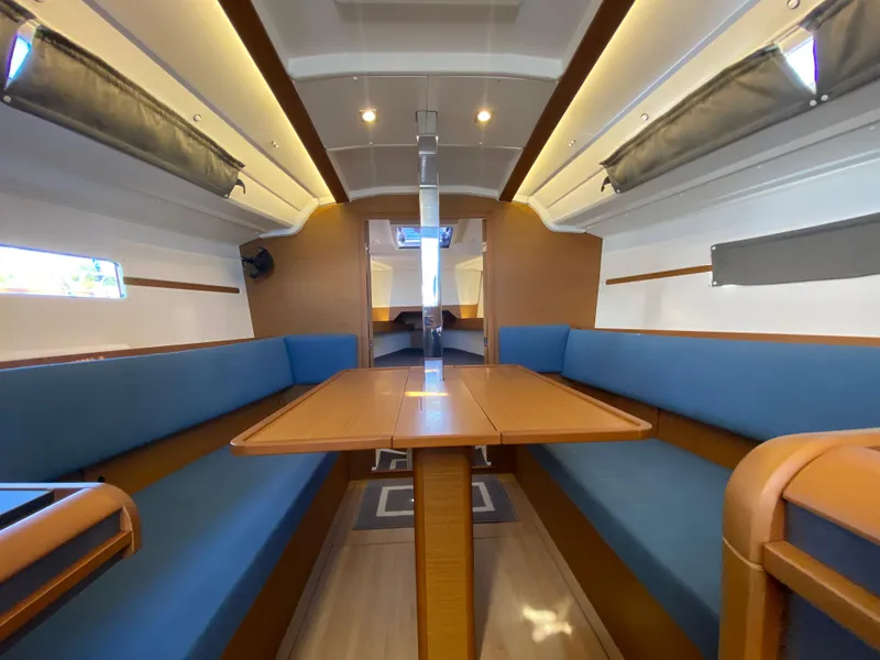 Slide: The Image of Interior of 2023 Jeanneau Sun Odyssey 349 sailboat with blue seating and wooden table. - 13