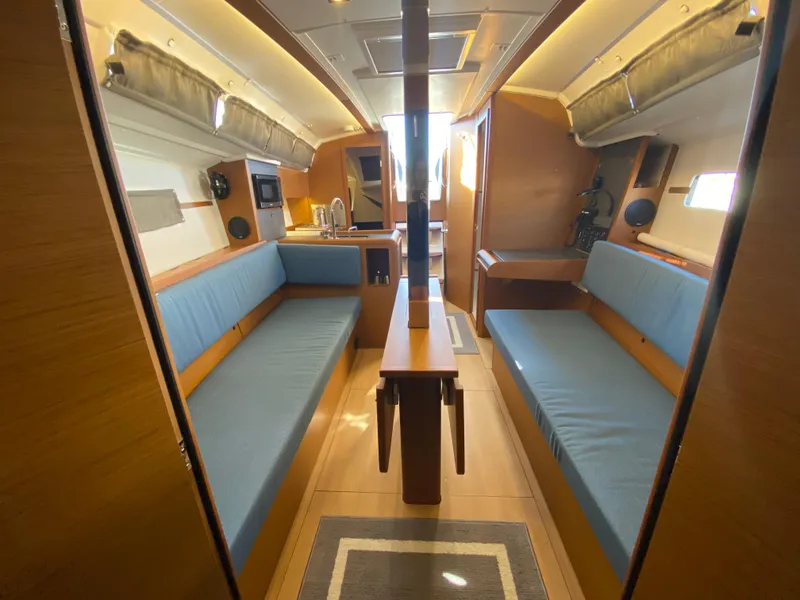Slide: The Image of 2023 Jeanneau Sun Odyssey 349 interior with blue seating and wooden finishes. - 14