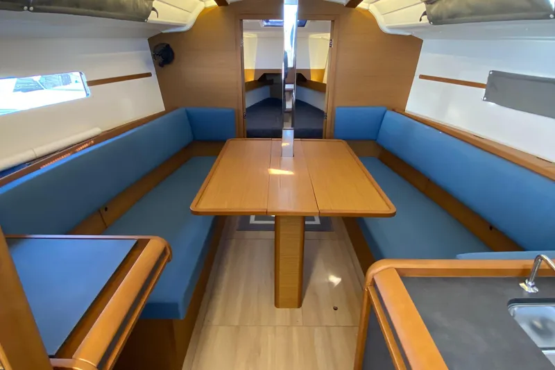 Slide: The Image of 2023 Jeanneau Sun Odyssey 349 interior with blue seating and wooden table. - 24