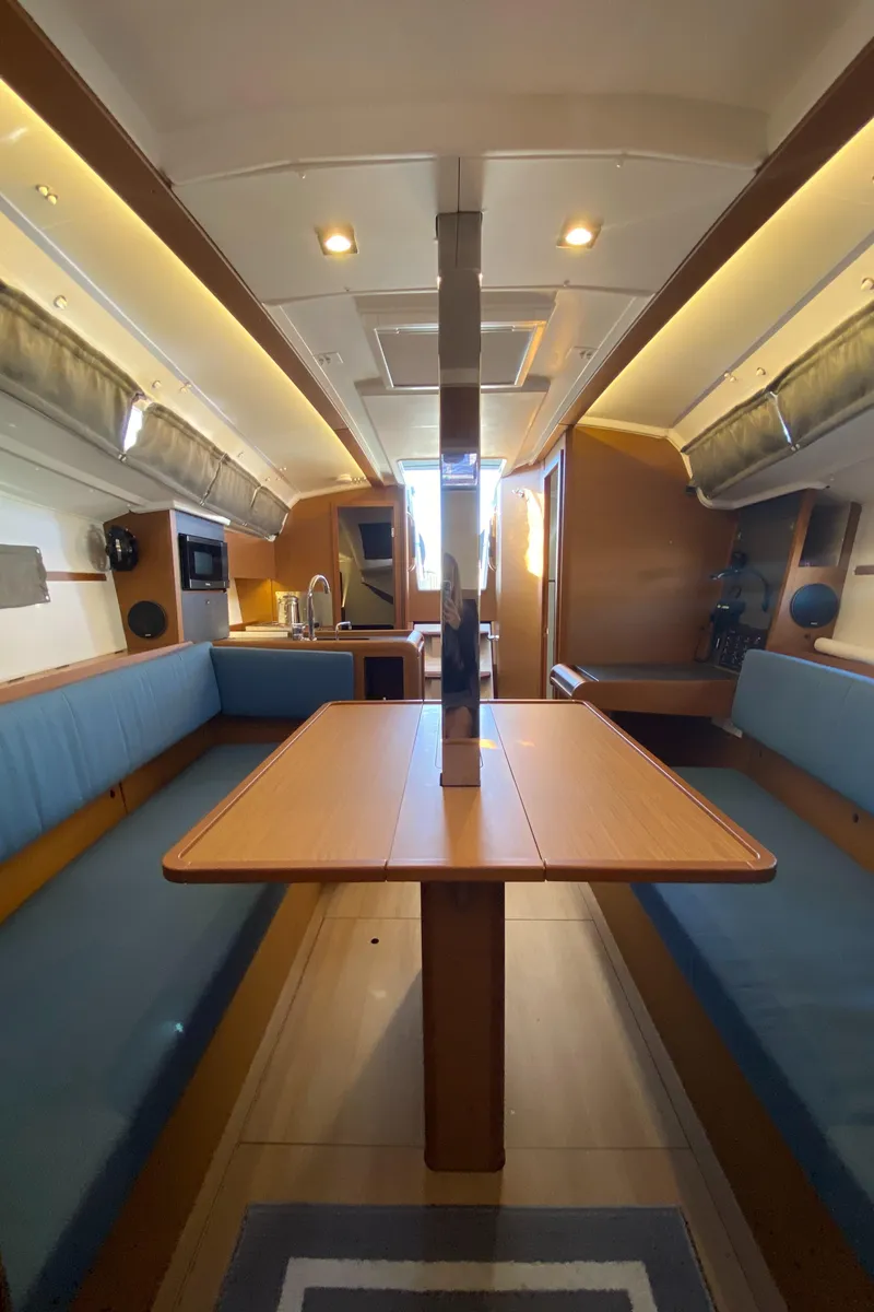 Slide: The Image of 2023 Jeanneau Sun Odyssey 349 interior with blue seating and wooden table. - 25