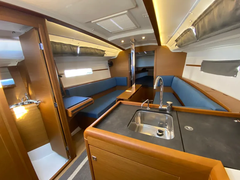 Slide: The Image of 2023 Jeanneau Sun Odyssey 349 interior with modern kitchen, seating, and wood finish. - 6