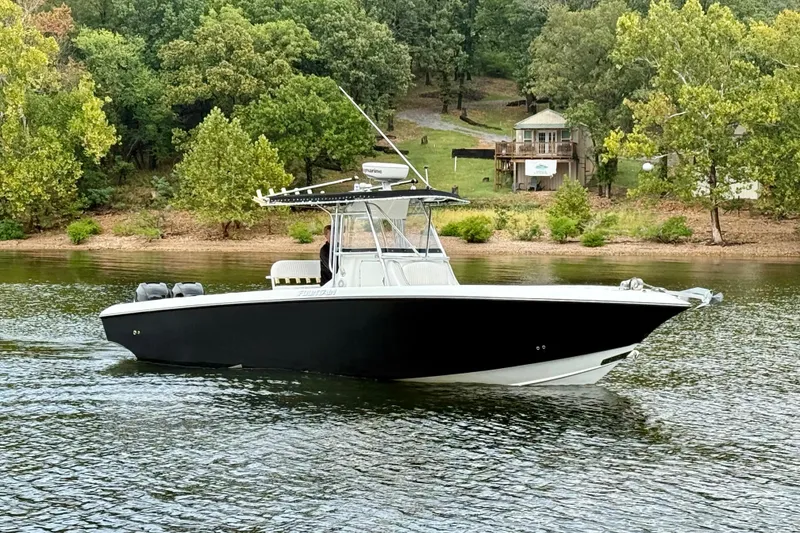 The Image of 2007 Fountain 32 Center Console boat on a serene lake with lush green trees. - 0
