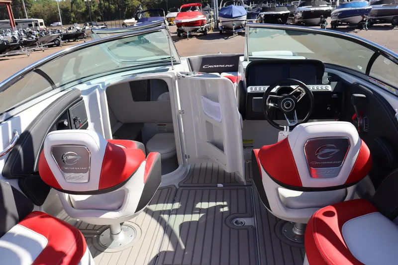 Slide: The Image of 2024 Crownline 260SS SURF boat interior with red and white seating, steering console, and open cabin door. - 13