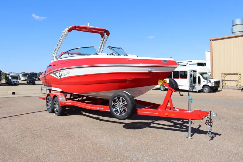 Slide: The Image of 2024 Crownline 260SS SURF boat on a red trailer in a parking lot. - 2