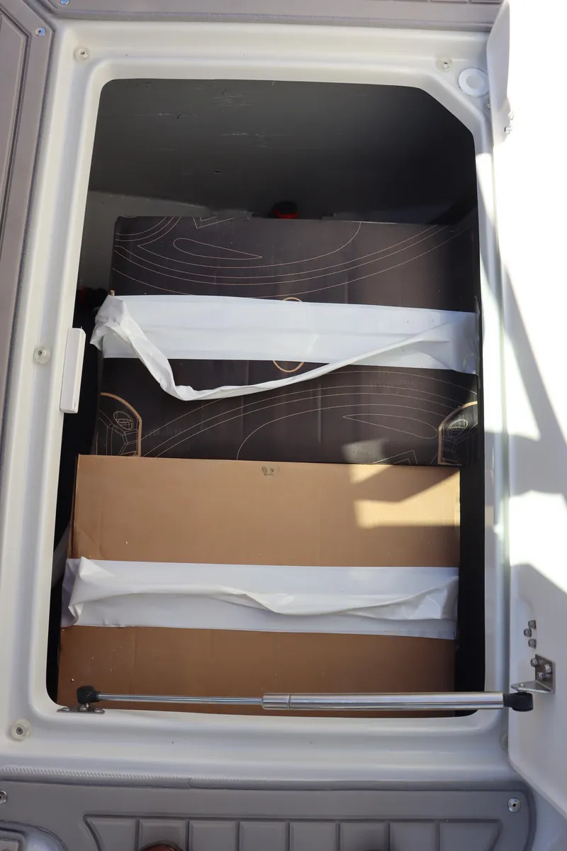 Slide: The Image of Storage compartment of 2024 Crownline 260SS SURF boat with secured items. - 21