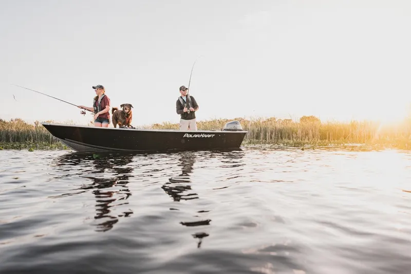Slide: The Image of 2024 Polar Kraft Dakota 1670 boat with people fishing on a serene lake. - 2