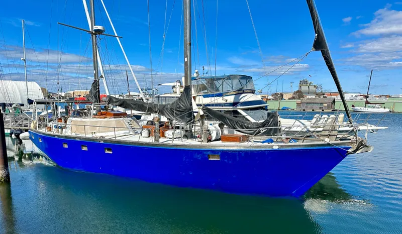 Slide: The Image of Blue 2000 Bruce Roberts Ketch sailboat docked in a marina under a clear sky. - 0