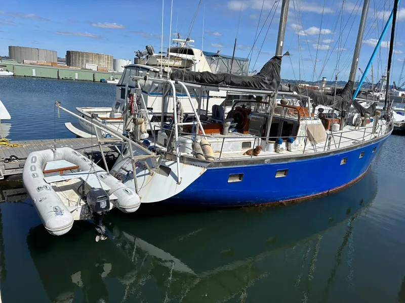 Slide: The Image of Blue Bruce Roberts Ketch sailboat docked in marina, 2000 model, with inflatable dinghy attached. - 1