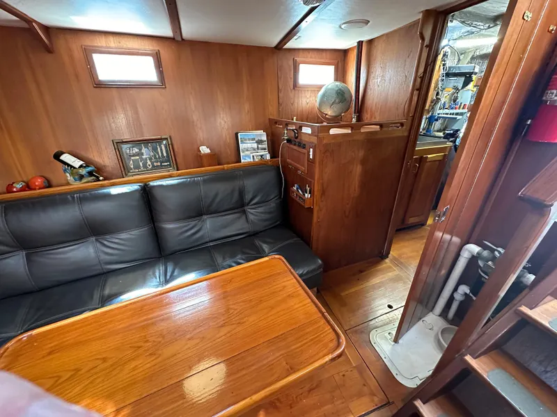 Slide: The Image of Interior of 2000 Bruce Roberts Ketch with wooden furnishings and black leather seating. - 33
