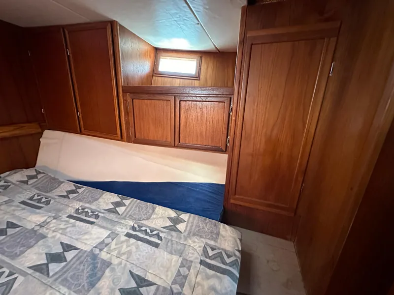 Slide: The Image of Cozy cabin interior of 2000 Bruce Roberts Ketch with wooden cabinets and patterned bedding. - 37