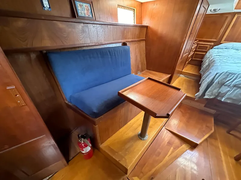 Slide: The Image of Interior of 2000 Bruce Roberts Ketch with wooden seating and table, blue cushion, and fire extinguisher. - 46