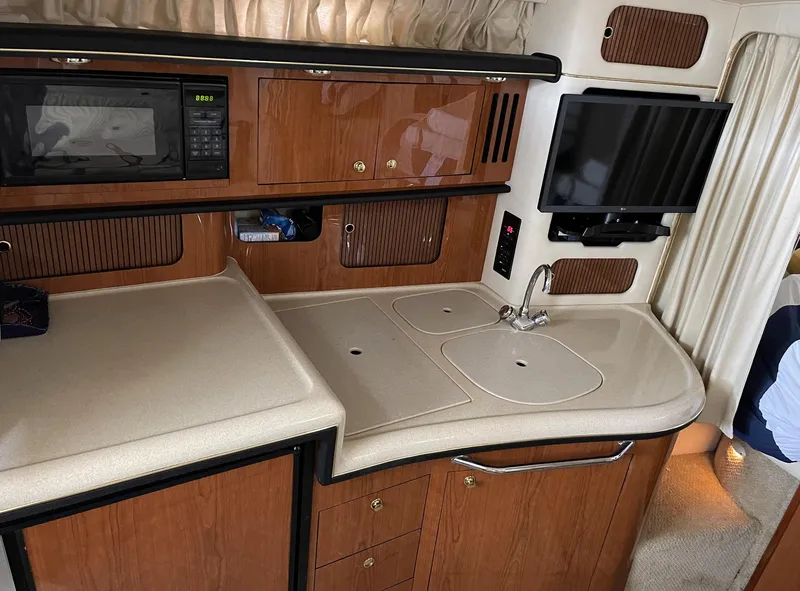 Slide: The Image of 2001 Sea Ray 340 Sundancer interior kitchen with sink, microwave, and TV. - 13