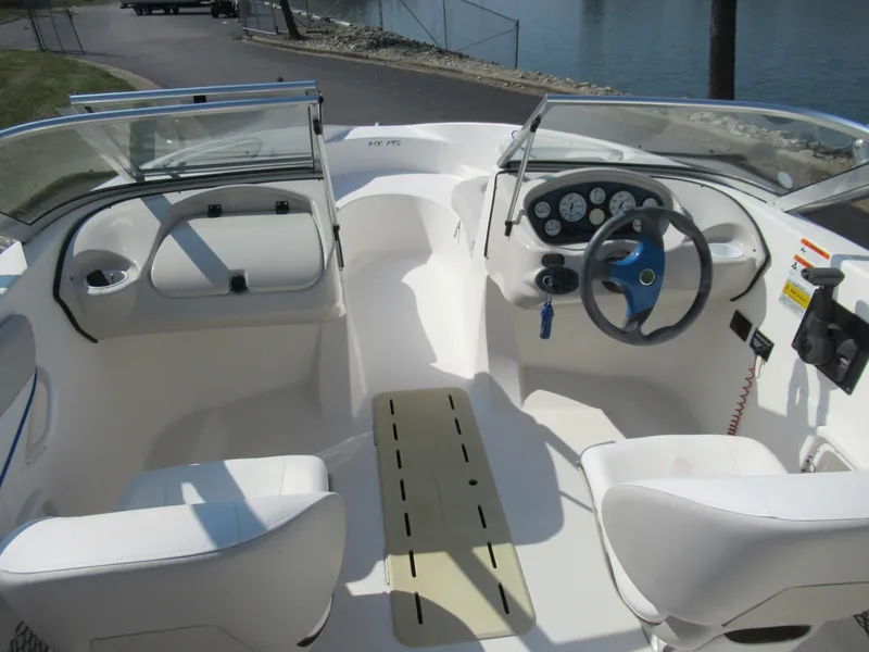 Slide: The Image of 2006 Glastron MX 195 boat interior with steering wheel and seating, docked by the water. - 12