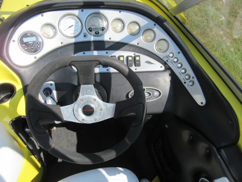 Slide: The Image of 2006 Tigé 22i boat dashboard with steering wheel and gauges, featuring a yellow and black design. - 13