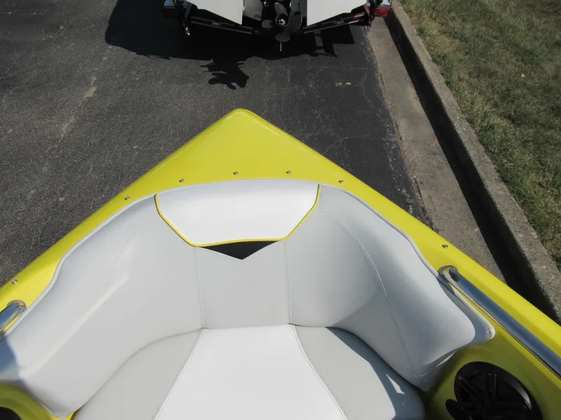 Slide: The Image of 2006 Tigé 22i boat with yellow and white seating, parked on pavement. - 17