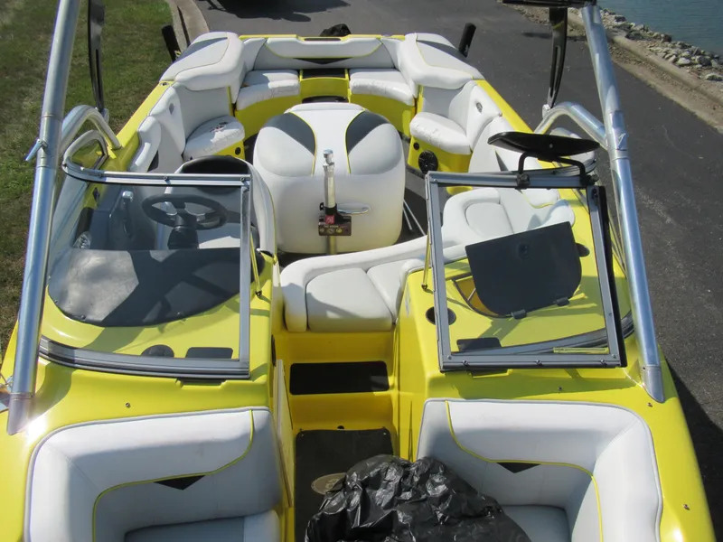 Slide: The Image of 2006 Tigé 22i boat interior with yellow and white seating, docked by the water. - 19