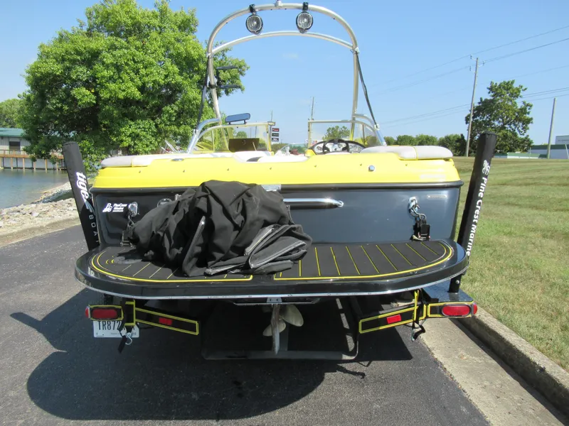 Slide: The Image of 2006 Tigé 22i boat with yellow and black detailing, parked near a waterfront. - 2