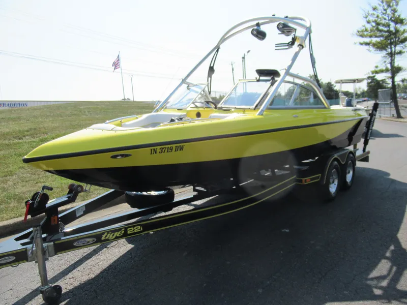 Slide: The Image of 2006 Tigé 22i boat in bright yellow on a trailer, parked outdoors. - 5