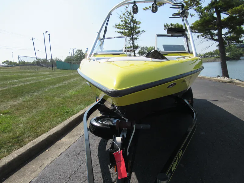 Slide: The Image of 2006 Tigé 22i yellow boat on trailer by lakeside road. - 6