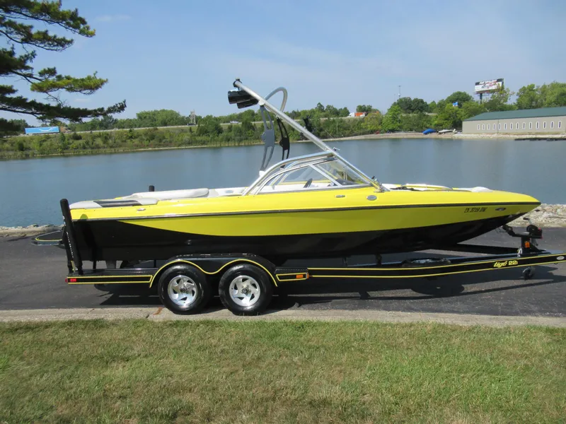 Slide: The Image of 2006 Tigé 22i boat in yellow and black by a lakeside. - 9