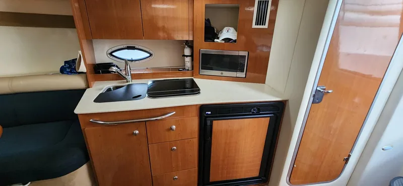 Slide: The Image of 2006 Maxum 3100 SE boat interior kitchen with sink, stove, and fridge. - 15
