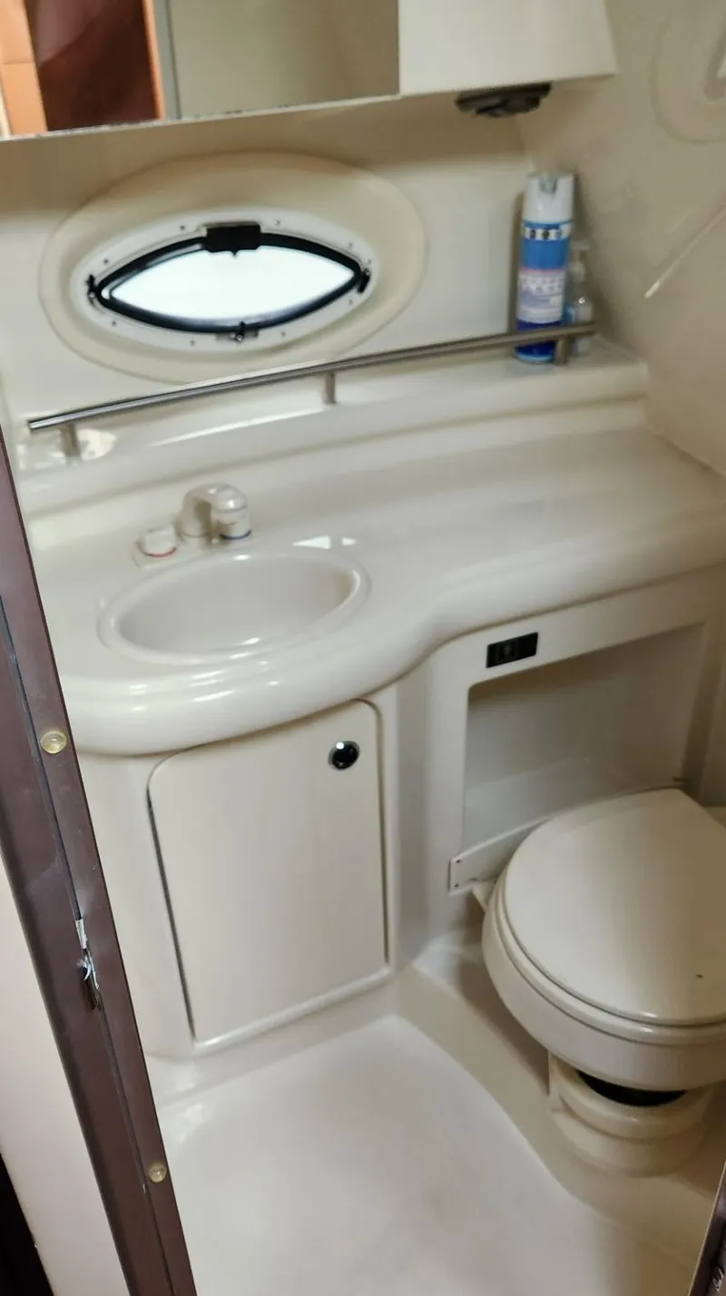 Slide: The Image of 2006 Maxum 3100 SE boat bathroom with sink, toilet, and oval window. - 18