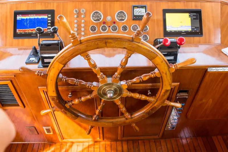 Slide: The Image of 1947 Trumpy Raised Pilot House helm with wooden wheel and modern navigation instruments. - 11