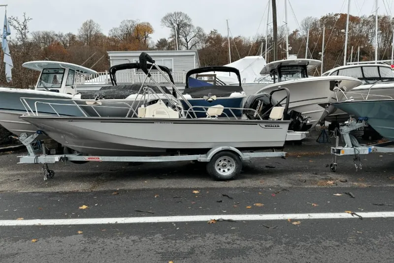 Slide: The Image of 2024 Boston Whaler 170 Montauk boat on trailer, parked among other boats. - 0