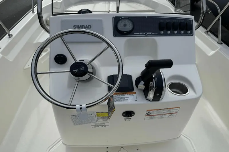 Slide: The Image of 2024 Boston Whaler 170 Montauk boat console with steering wheel and controls. - 10