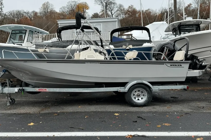 Slide: The Image of 2024 Boston Whaler 170 Montauk boat on a trailer, parked outdoors. - 2