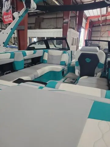 Slide: The Image of 2023 Malibu M220 boat interior with teal and white seating in a showroom. - 3