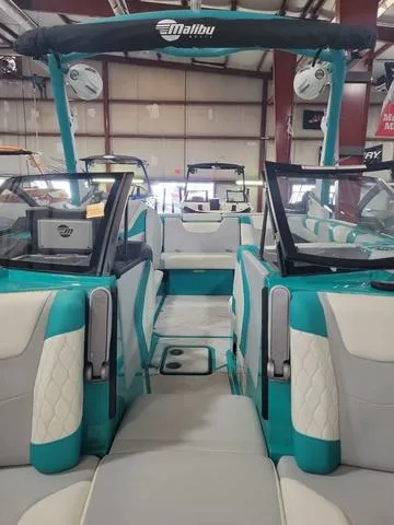 Slide: The Image of 2023 Malibu M220 boat interior with teal and white seating in showroom. - 7