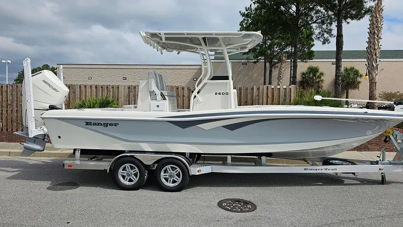 Slide: The Image of 2024 Ranger 2600 Bay boat on a trailer, side view, white hull, outdoor setting. - 12