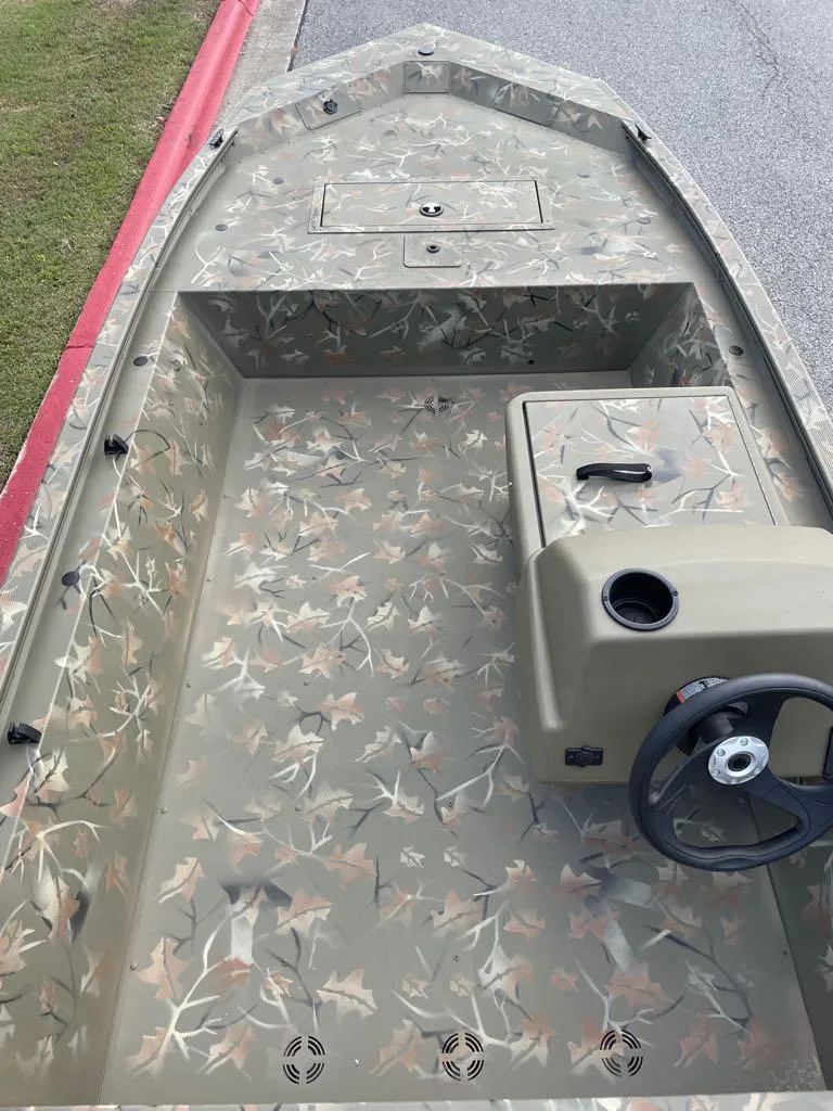 Slide: The Image of 2024 Tracker Grizzly 1648 SC boat with camouflage interior and steering console. - 2