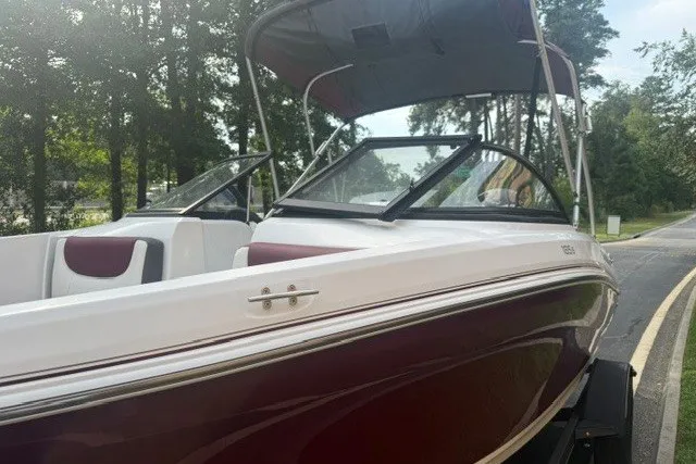 Slide: The Image of 2024 Tahoe 185 S boat with canopy, parked on a tree-lined road. - 9